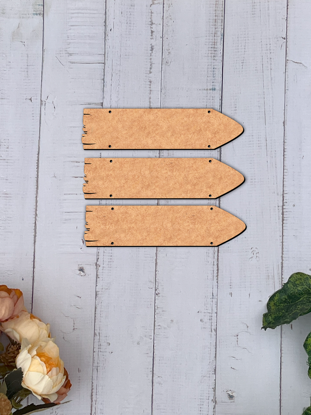 Three wooden arrow-shaped signs on a light MDF board with floral and leaf decorations.
