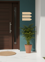 Decorative wall art with three MDF board arrows on a teal wall next to a plant and door.