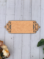 Decorative MDF board nameplate on a light wooden surface with floral elements.