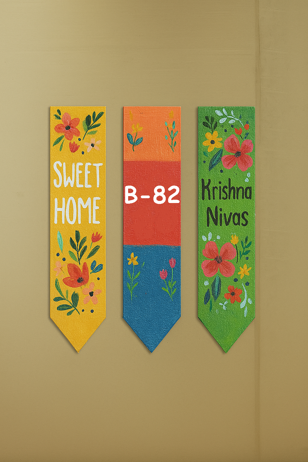 Three colorful decorative MDF name plate with floral designs and text on a beige wall.