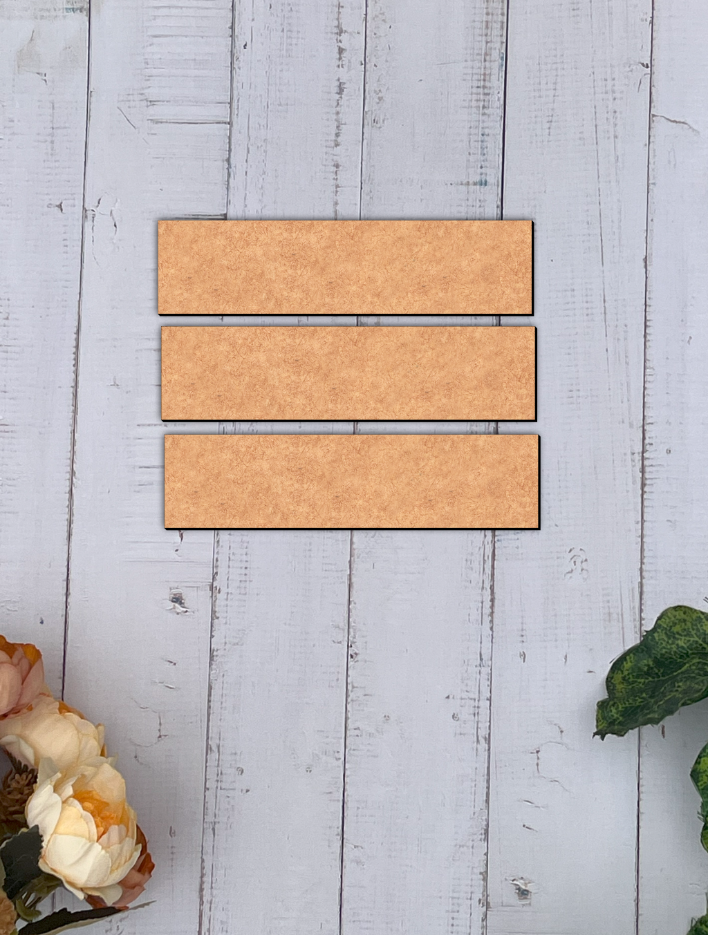 Three MDF board slats on a light gray wooden surface with floral and leaf decorations.