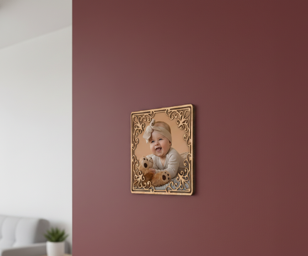 Decorative photo frame of a baby holding a teddy bear on a maroon wall.