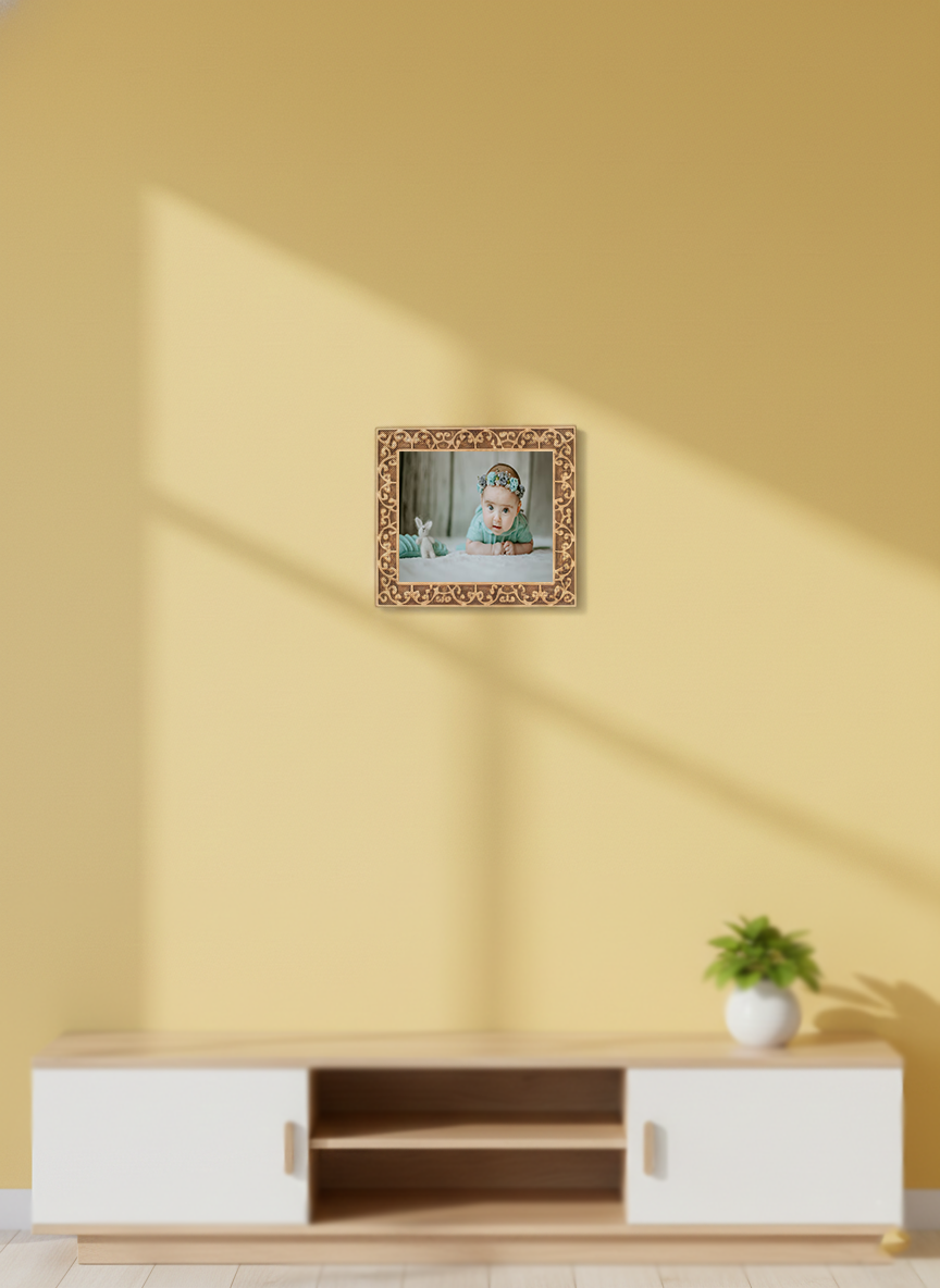 Digital photo frame on a yellow wall with a plant below.
