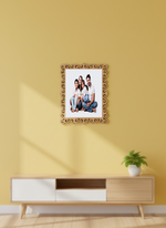 Decorative photo frame with a family portrait on a yellow wall above a wooden cabinet.