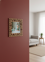 Decorative photo frame with floral frame on a red wall in a living room.