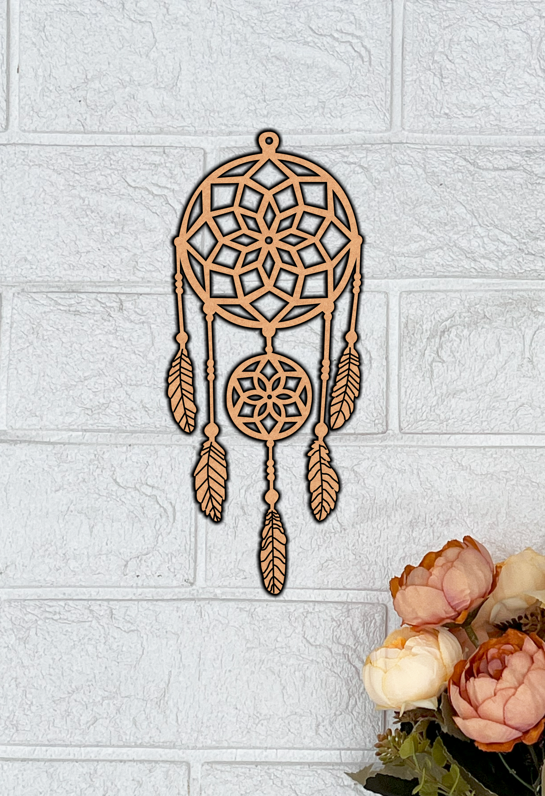 MDF dreamcatcher on a textured white wall with flowers at the bottom right corner.