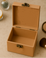 Open tan jewelry box on a beige surface with makeup items around