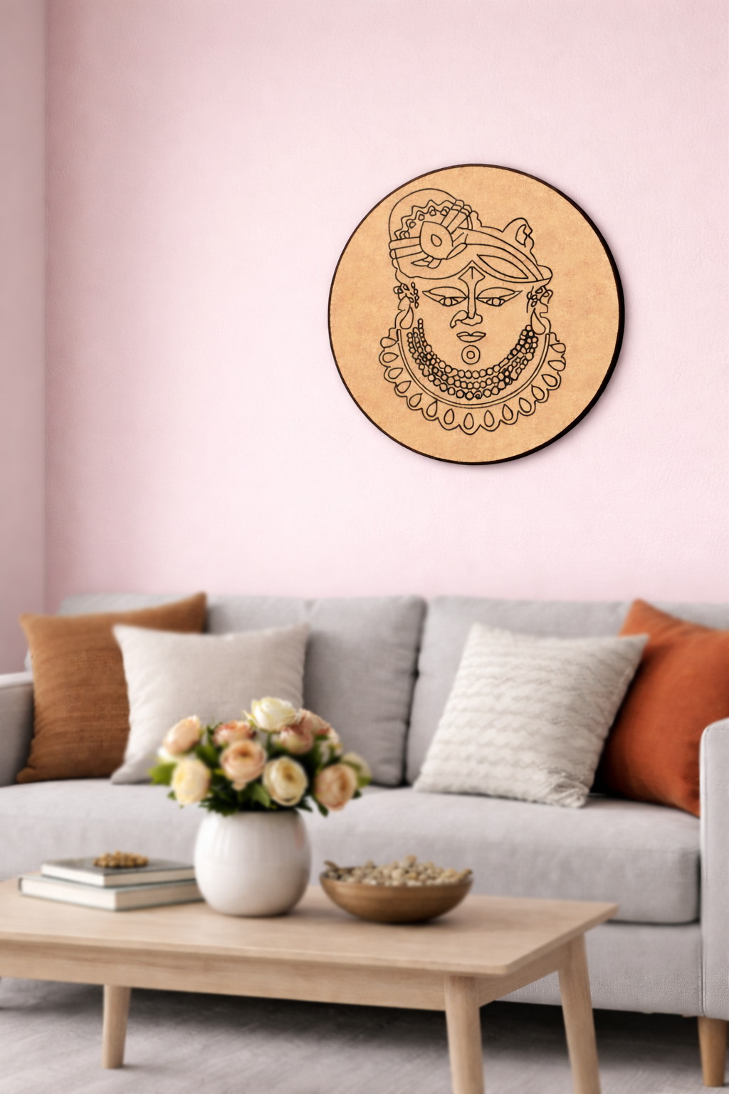 Decorative MDF DIY wall art of a face with a crown on a pink wall above a gray sofa.