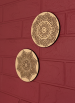 Two MDF DIY wall art  with intricate mandala designs on a red brick-patterned surface.