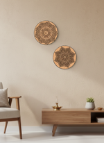 Two decorative MDF DIY wall hangings with mandala patterns on a beige wall above a wooden coffee table.