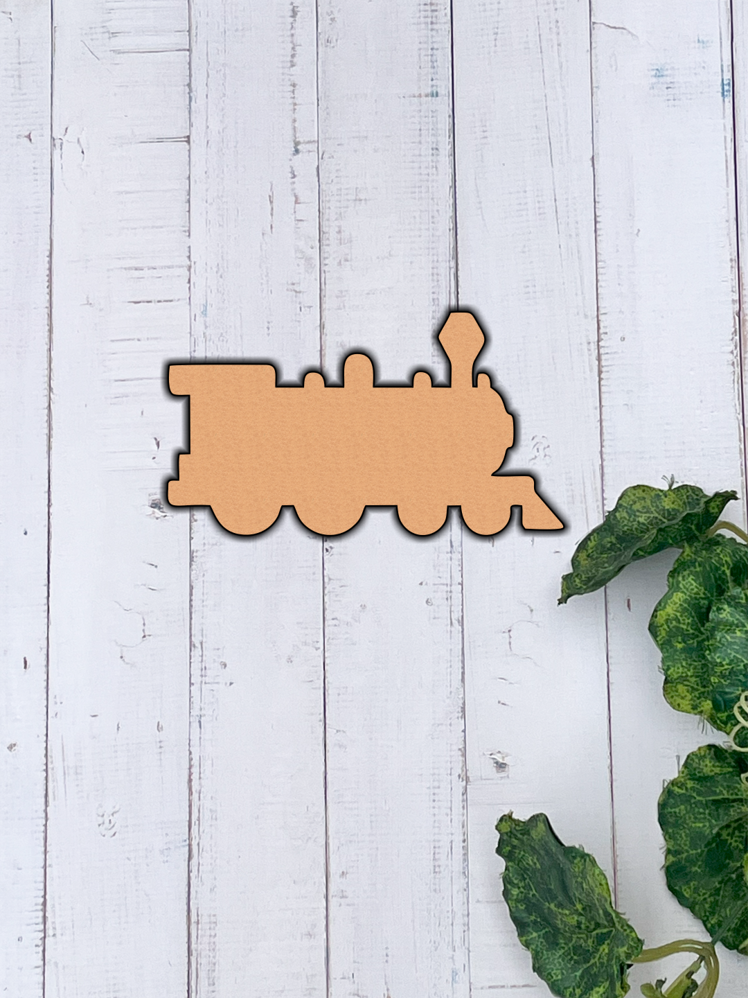 Unpainted MDF steam train engine cutout with multiple rounded wheels, a tall front lamp shape, and simple silhouette details, hanging on wooden wall