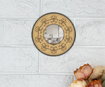Round wall mirror with floral patterns on a textured white wall.