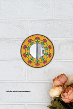 Decorative wall mirror with floral design on a white tiled wall.