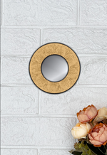 Round MDF wall mirror with floral engraved frame on white textured wall