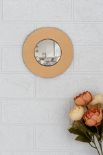 Round DIY wall mirror on a light gray tiled wall with flowers in the foreground.