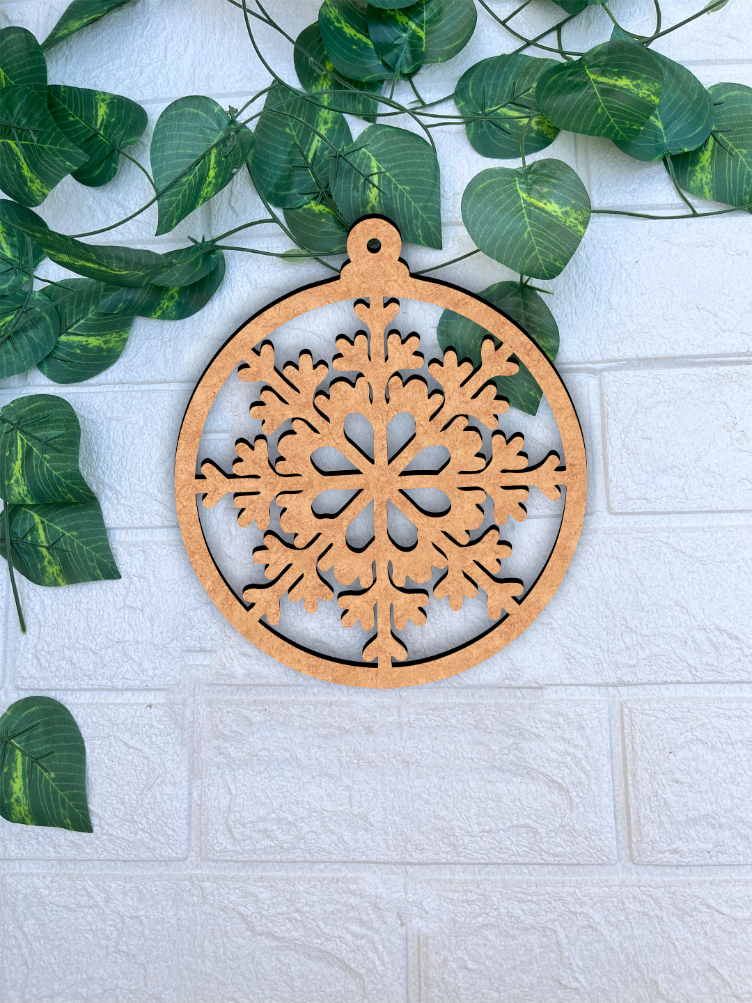 Round DIY MDF floral snowflake ornament cutout with hanging loop, paintable Christmas craft mounted on white bricks wall
