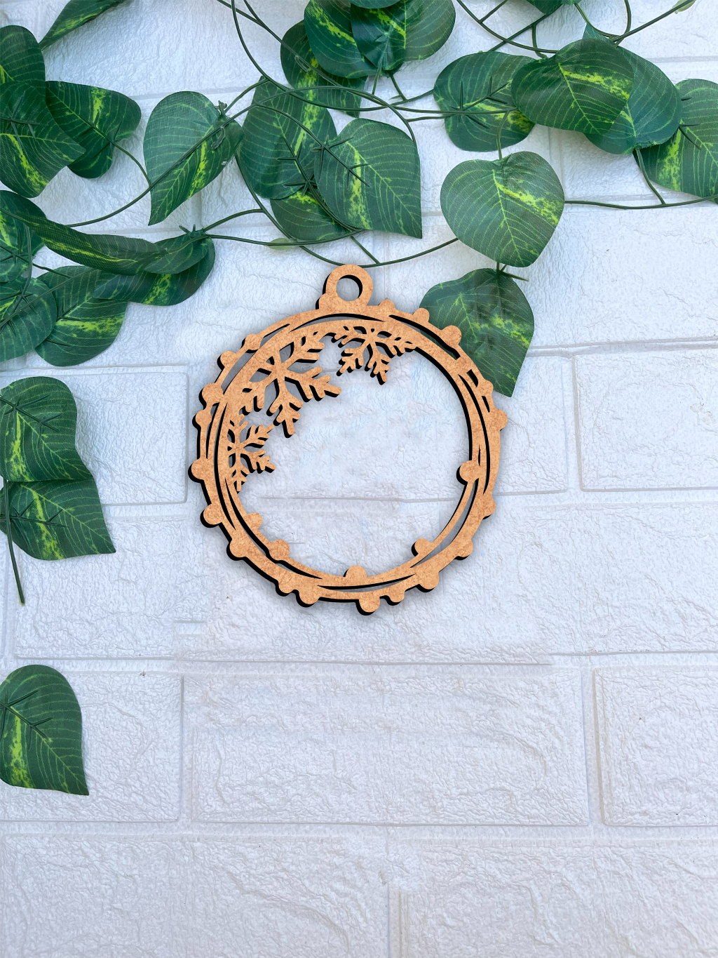 Laser-cut DIY MDF snowflake ring ornament cutout with hanging loop, Christmas decoration mount on white brick wall