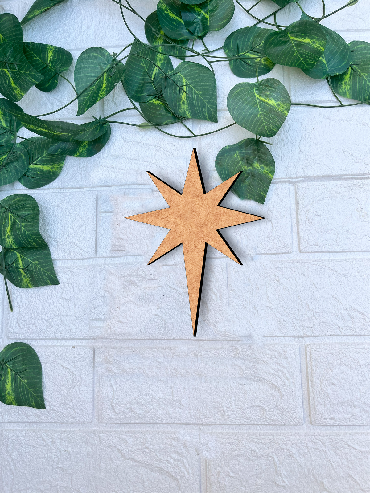 DIY MDF star cutout for Christmas craft mounted on white brick wall