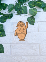 Unpainted MDF Santa Claus waving DIY cutout on white brick background with green vine leaves.