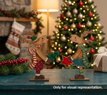 Two DIY MDF reindeer figurines in front of a decorated Christmas tree.