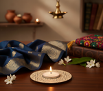 Decorative setup with a lit candle, blue fabric, and white flowers on a wooden surface with mdf tealight candle holder.