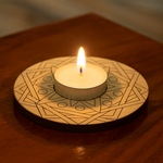 Candle on a decorative wooden coaster with geometric patterns on a wooden surface with mdf tealight candle holder.