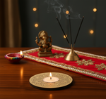Decorative setup with a lit candle, small statue, and incense sticks on a red cloth with mdf tea light candle holder.