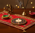 Decorative setup with a lit candle, diya, and Ganesha idol on a red cloth with handpainted tea light candle holder.