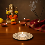 Decorative setup with a statue, flowers, candles, and incense on a wooden surface with mdf tea light candle holder in centre.
