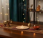 Decorative setup with incense sticks, candles, and an elephant figurine on a table with mdf tea light candle holder in the centre.