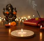 Candle on a decorative stand with a statue of Ganesha and flowers in the background with mdf tea light candle holder.