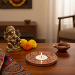 Decorative setup with a statue, candles, and flowers on a wooden table.