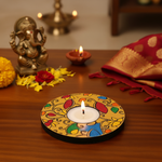 Decorative candle on a colorful holder with a statue of Ganesha and traditional items on a wooden table with handpainted mdf tealight candle holder.