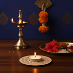 Decorative setup with a lit candle, brass lamp, and marigold flowers on a wooden surface with MDF tea light candle holder on it.