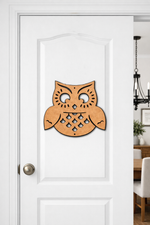 MDF DIY owl decoration on a white door with a dining area in the background