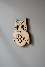 MDF DIY owl wall art on a red wall with two beige armchairs and a small table.
