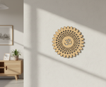 Decorative MDF DIY wall art with a central symbol on a light wall, with a wooden cabinet and plant in the background.