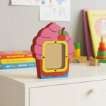 DIY MDF cupcake shaped Money bank on a shelf with books and toys in the background.
