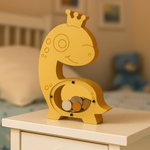 DIY MDF dinosaur-shaped money box with a crown on a wooden surface.