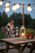 Outdoor table with candle lantern under string lights