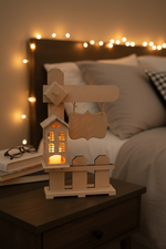 MDF lantern with nameplate placed on bedside table, lit with warm candlelight.