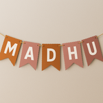 Bunting with the name 'MADHU' on a beige background