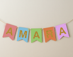 Colorful banner with 'AMARA' in glittery letters on a beige background