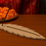Decorative MDF feather incense holder with unlit incense stick and marigold flowers.