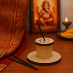 Burning incense stick in cylindrical holder, Ganesha idol and diya in background.