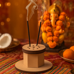 MDF incense stick holder with one incense stick, Ganesh idol in background.