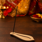 Burning incense stick placed in MDF teardrop incense holder on festive setup