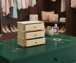 MDF DIY Jewellery Box with drawers on a green surface, with clothing and bags in the background.