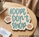 MDF DIY sign with 'Adopt Don't Shop' text on a wooden table.