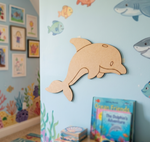 MDF DIY dolphin cutout on a wall with children's books and colorful decorations in a room.